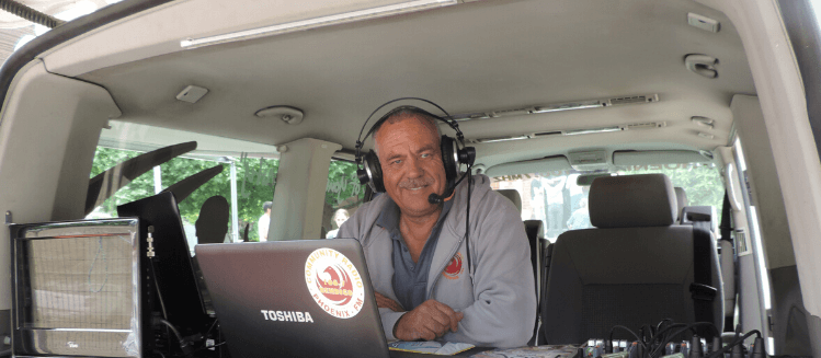 Smiling man with headphones in outside broadcast van