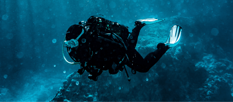 A deep diver wearing wetsuit, mask and flippers in a blue sea