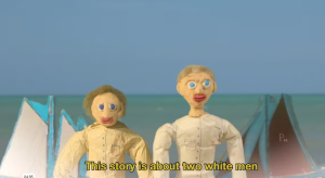 Two hand crafted people standing in front of water with sub title This story is about two white men