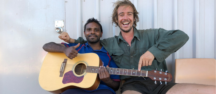 Archer and Wilcannia local Eric holding a guitar