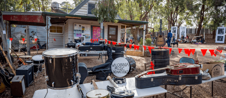 Wilcannia River instrument donation concert at Lot 19 with instruments displayed on table in the foreground