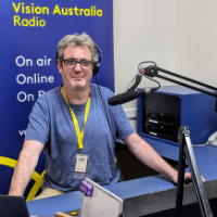 Vision Australia presenter with headphone in the studio behind a microphone