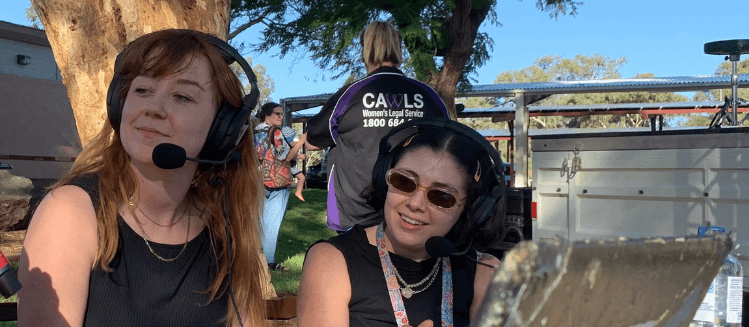 Two female presenters from 8CCC wearing headsets at an outdoor broadcast