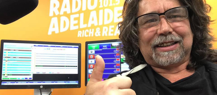 Smiling man using the thumbs up sign in front of the Radio Adelaide branding