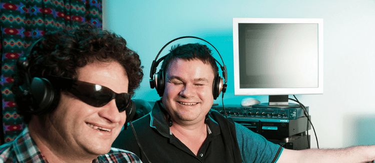 Two vision impaired men in studio smiling