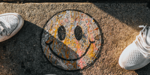 Happy face chalked onto concrete with two feet standing near by