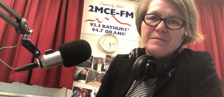 Woman in studio with 2MCE-FM poster in background